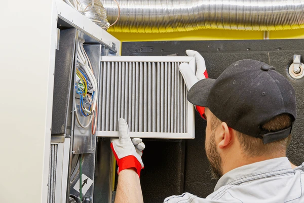 HVAC technician replacing furnace filter in West Bloomfield MI