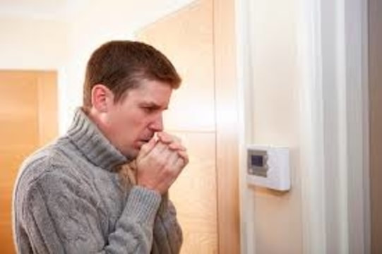Man cold looking at thermostat